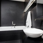 Hvit rørleggerflate på badet i svart interiør