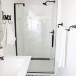 Mažas baltas vonios kambarys su grindų raštais