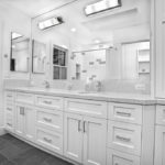 Phòng tắm màu trắng với sàn gạch màu xám và bàn làm việc bằng đá granit trắng