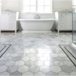 Baño blanco con azulejos de panal gris y blanco en el piso
