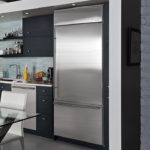 Gray metallic refrigerator in the interior of the black and white kitchen