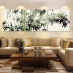 Japāņu stila horizontālo triptihu gleznas viesistabas interjerā