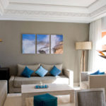 Gleznas viesistabas interjerā ar triptihu zilu akcentu