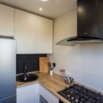 Drevená pracovná doska a svetlé skrinky v kuchyni mestského bytu