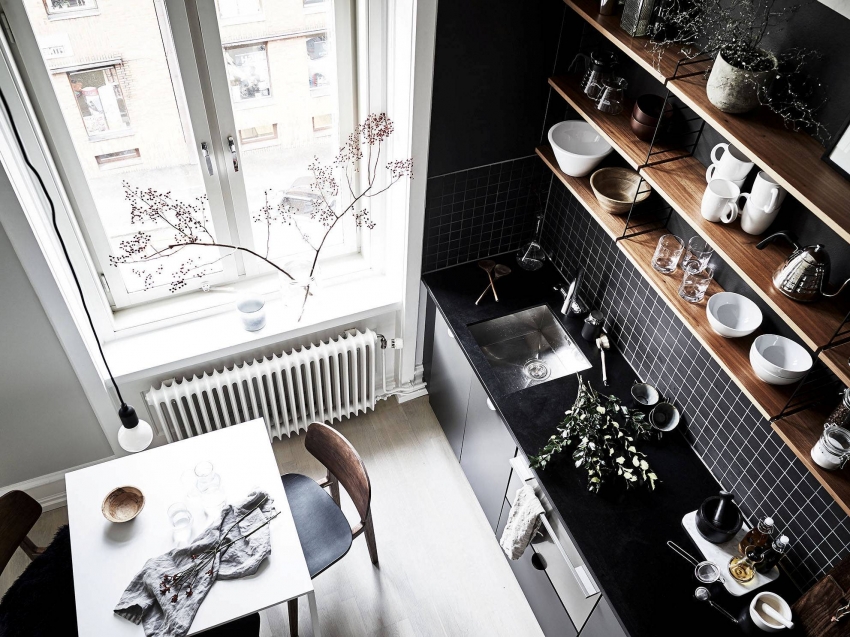 Interior da cozinha em preto e branco com prateleiras de madeira.