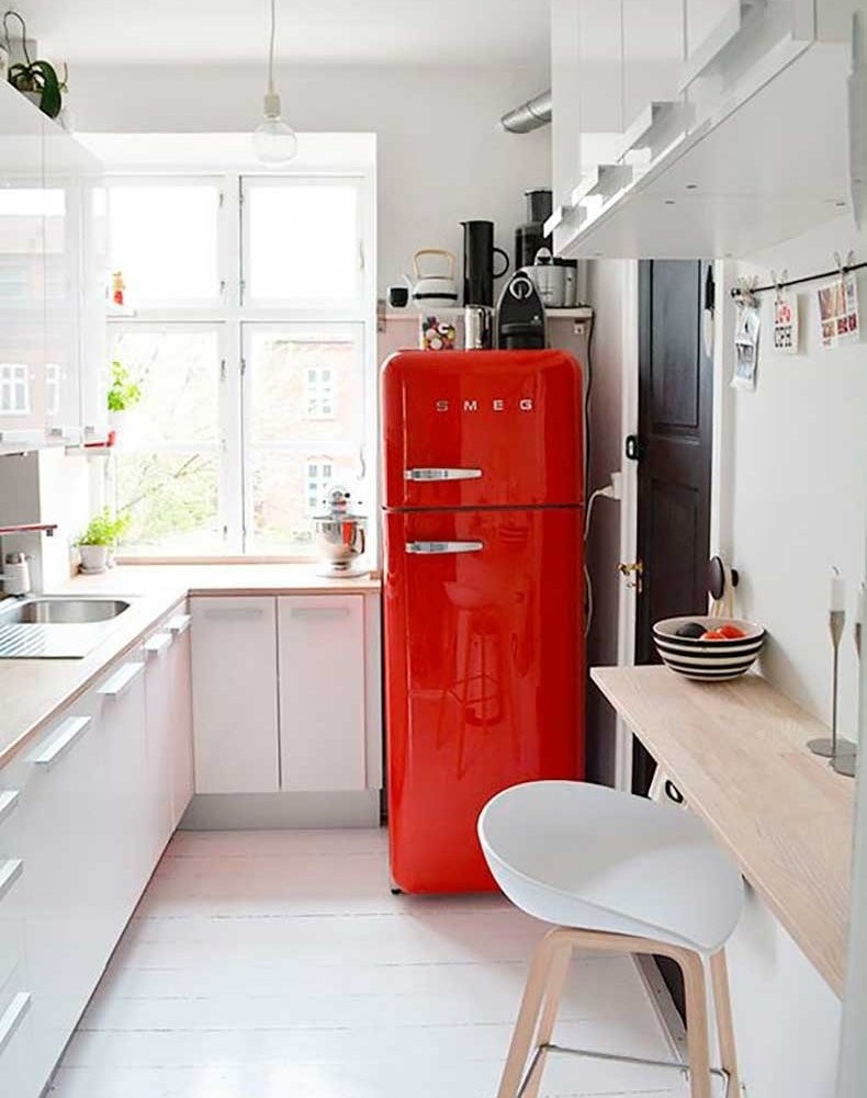 Color rojo como acento en la cocina con gabinetes blancos.
