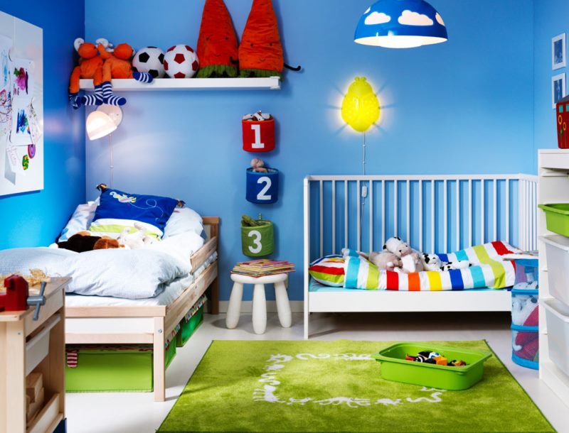 Two different cribs in a nursery with blue walls