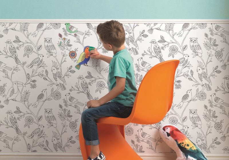 De jongen schildert papierbehang op de muur van een kinderkamer