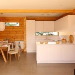 Cozinha branca estrita na casa com guarnição de madeira