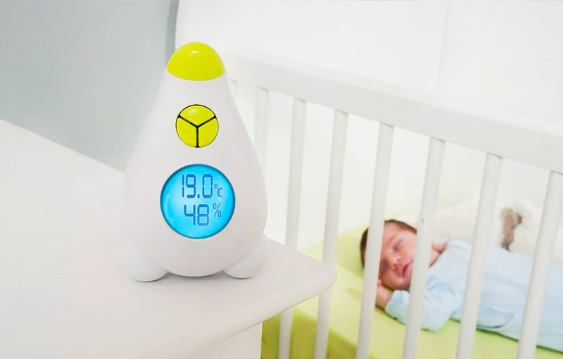 Thermometer in de buurt van de wieg met een pasgeborene