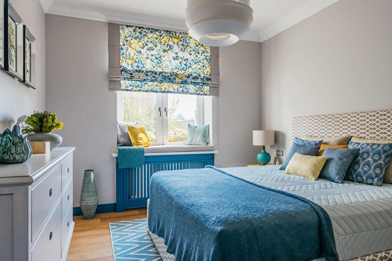 Zila gultas pārklājs guļamistabā ar pelēkām sienām