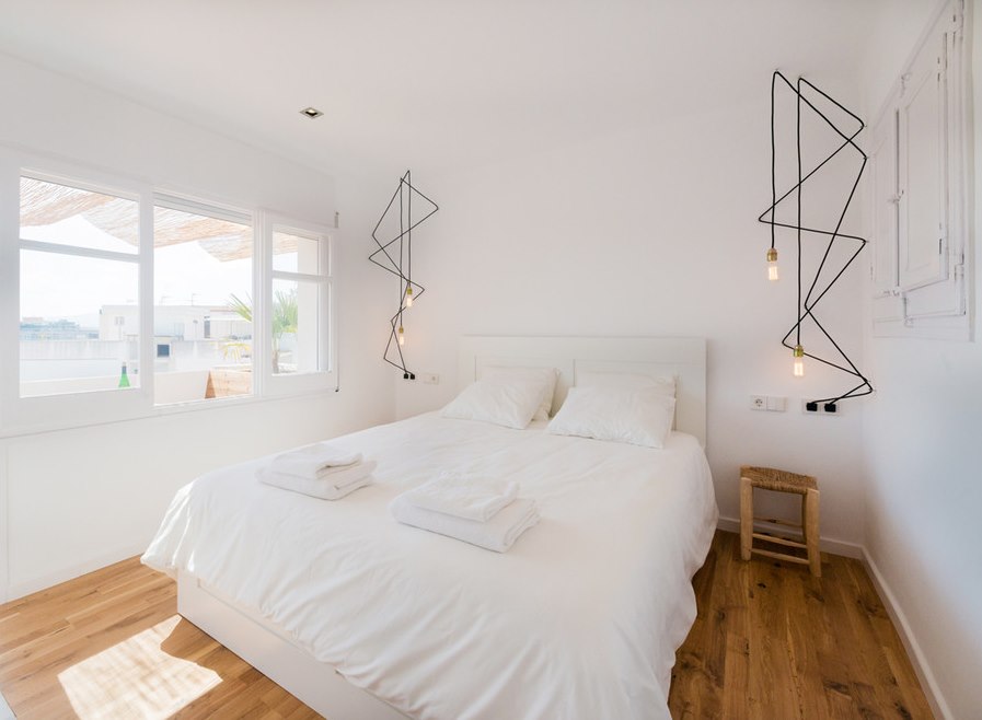 Original lighting in a white bedroom in a minimalist style.