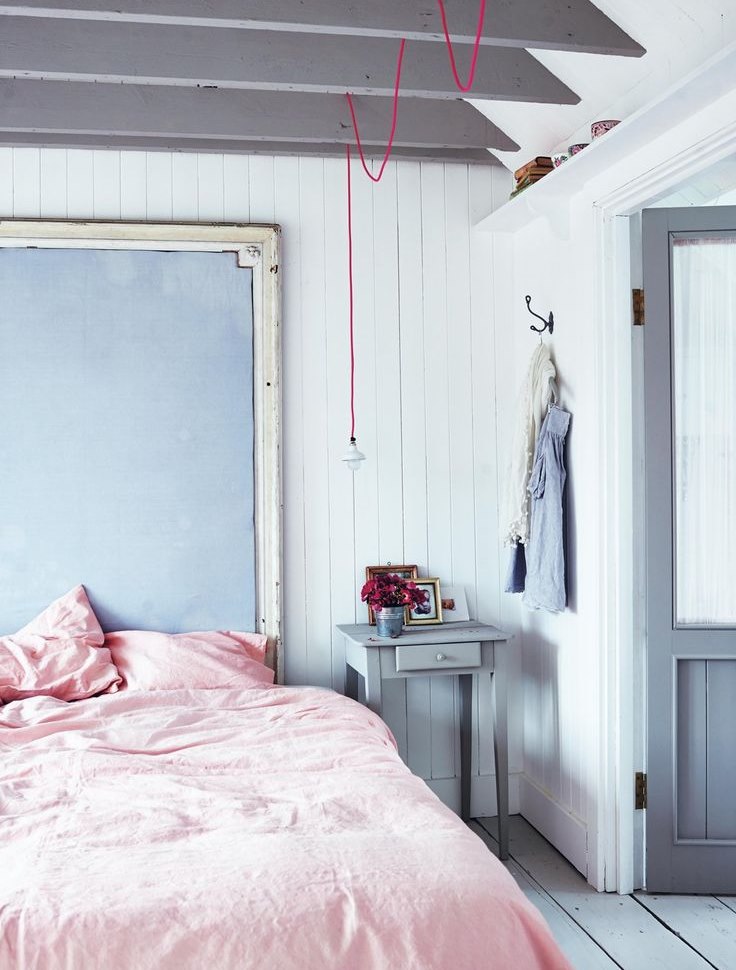 ผ้าคลุมเตียงสีชมพูในห้องนอนที่มีผนังสีฟ้า