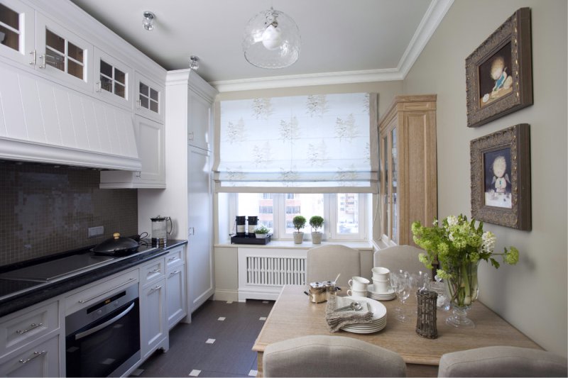 An elongated kitchen with a Roman curtain on the window