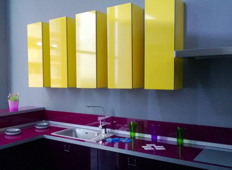 Dzelteni piekārti skapīši virtuvē ar purpursarkanām virsmām