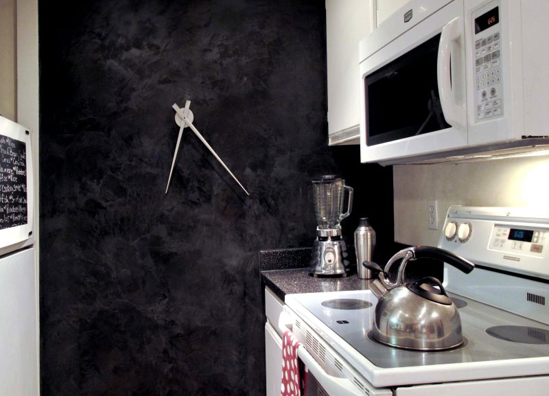 Dizaineru pulkstenis uz mazas virtuves tumšās sienas