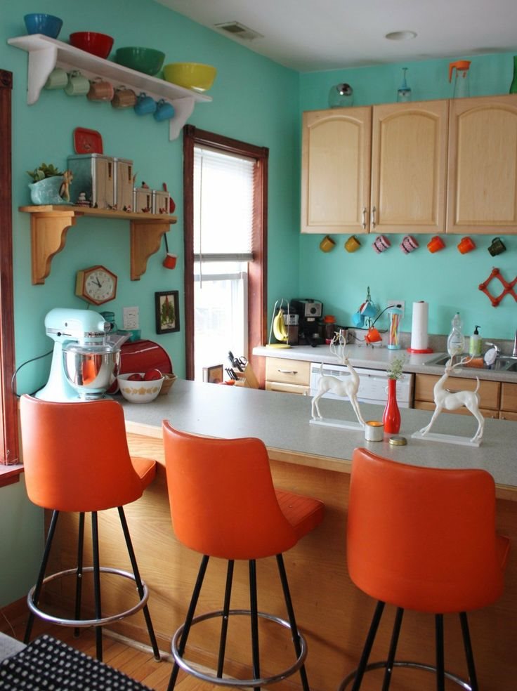 Piparmētru sienas virtuvē ar oranžiem krēsliem