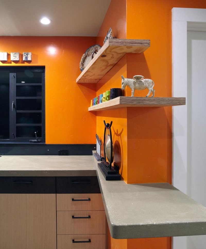Wooden shelves on an orange kitchen wall
