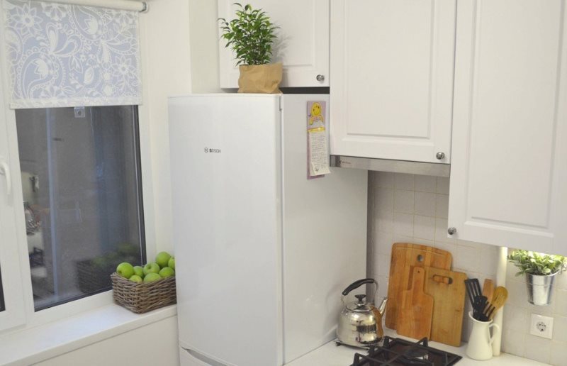 Fehér hűtőszekrény a konyhaablak közelében