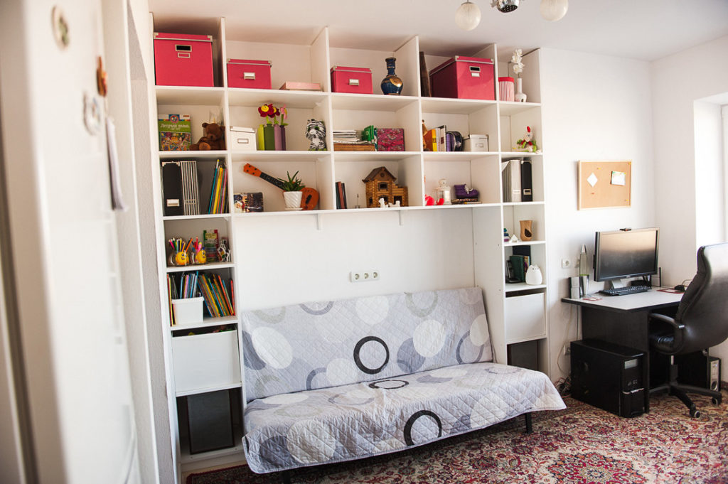 Open shelves above a sofa in a white kitchen-living room