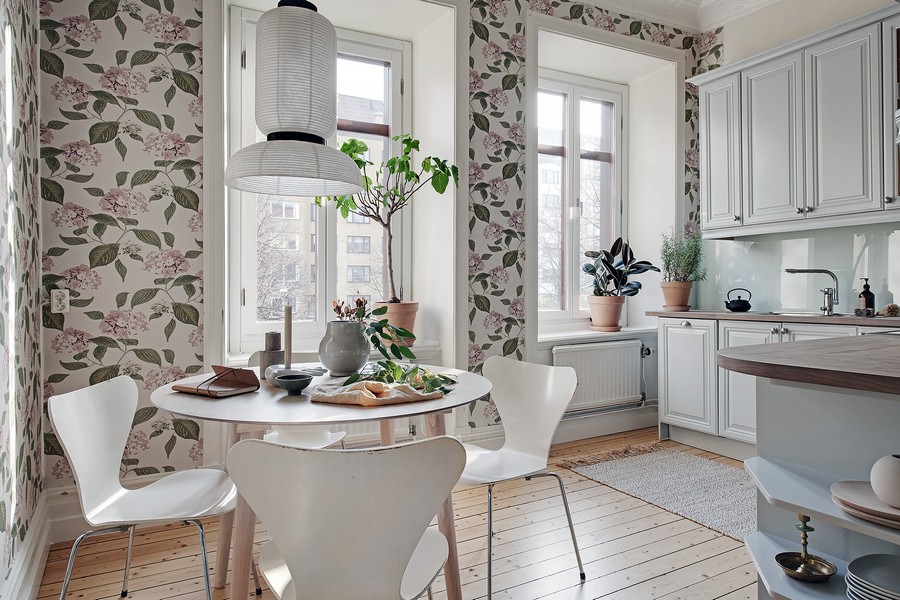 Folhas verdes no papel de parede na cozinha com móveis brancos