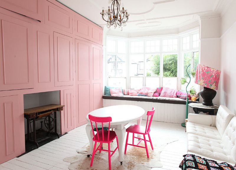 Roze stoelen rond een witte ovale tafel