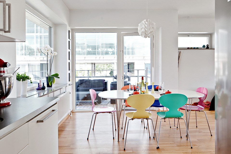 Stoelen van verschillende kleuren in de keuken met witte muren