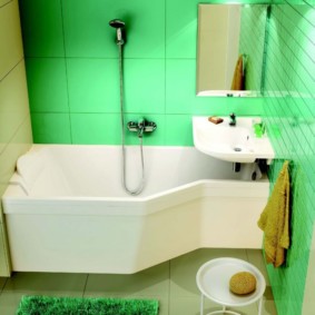 Balta santehnika vannas istabā ar zaļām sienām