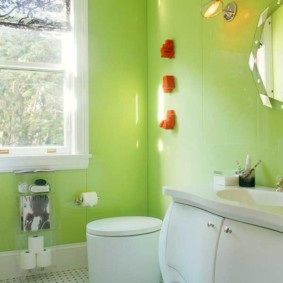 Balta tualete telpā ar zaļām sienām