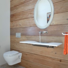 Toaleta suspendată de perete pe un perete de casă din lemn
