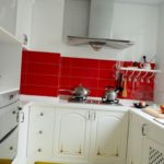 Raudona prijuostė baltoje virtuvėje