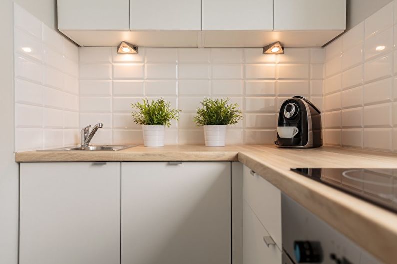 Små lamper under hengeskapene på et kompakt kjøkken