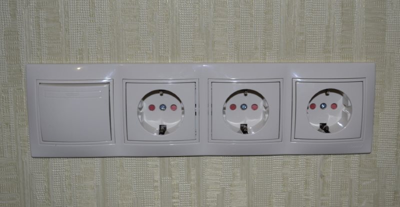 Kontaktligzdas bloks ar slēdzi pie sienas blakus vannas istabai