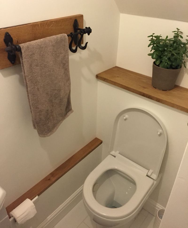 Floare de interior pe un raft din lemn în toaletă