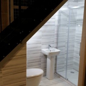 Shower cabin under the stairs in a wooden house