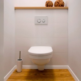 Wooden shelf over a hinged toilet