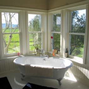 Bañera en una habitación con ventanas de madera.