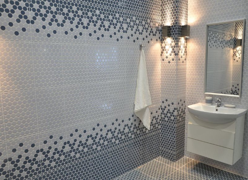 Mosaico blanco y gris en la pared del baño.