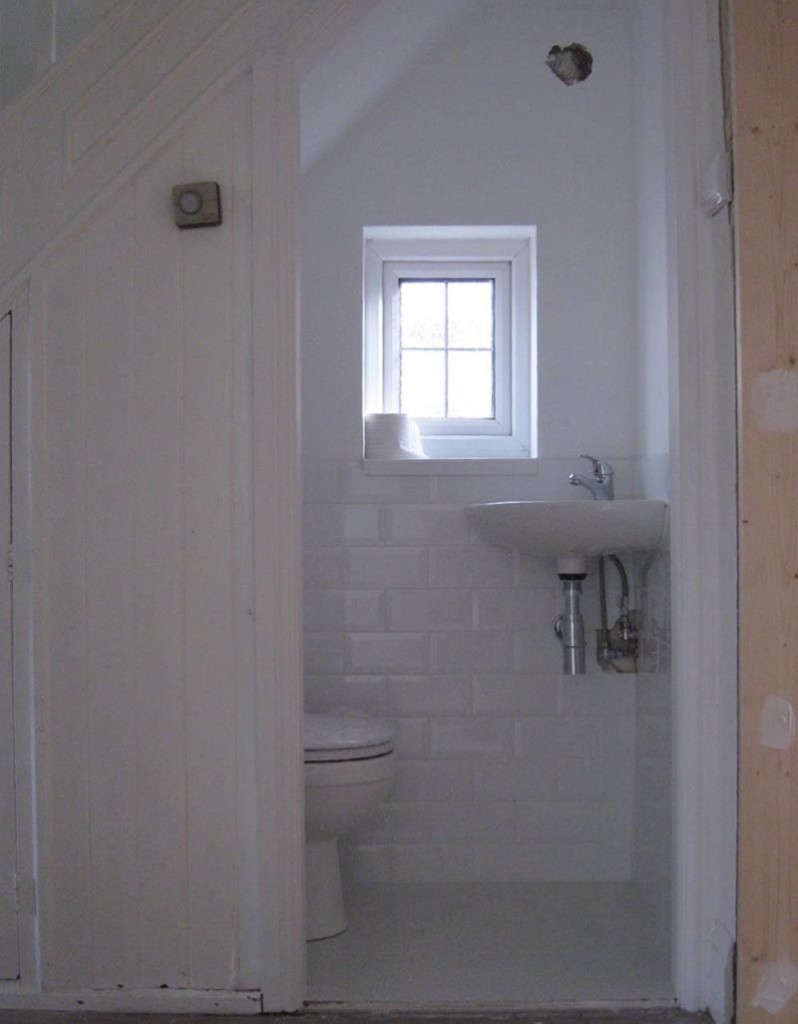 A small window in the toilet under the stairs