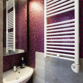 White heated towel rail in the mosaic bathtub