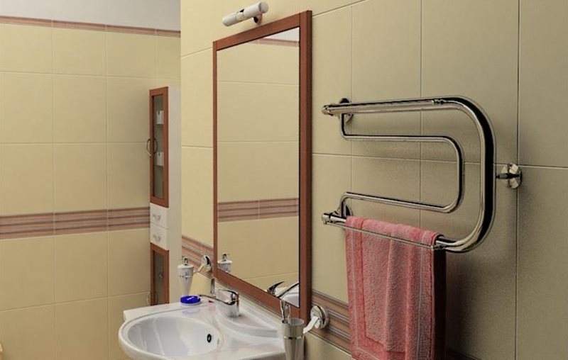 Vodou zahřívaná věšák na ručníky na zdi vedle zrcadla