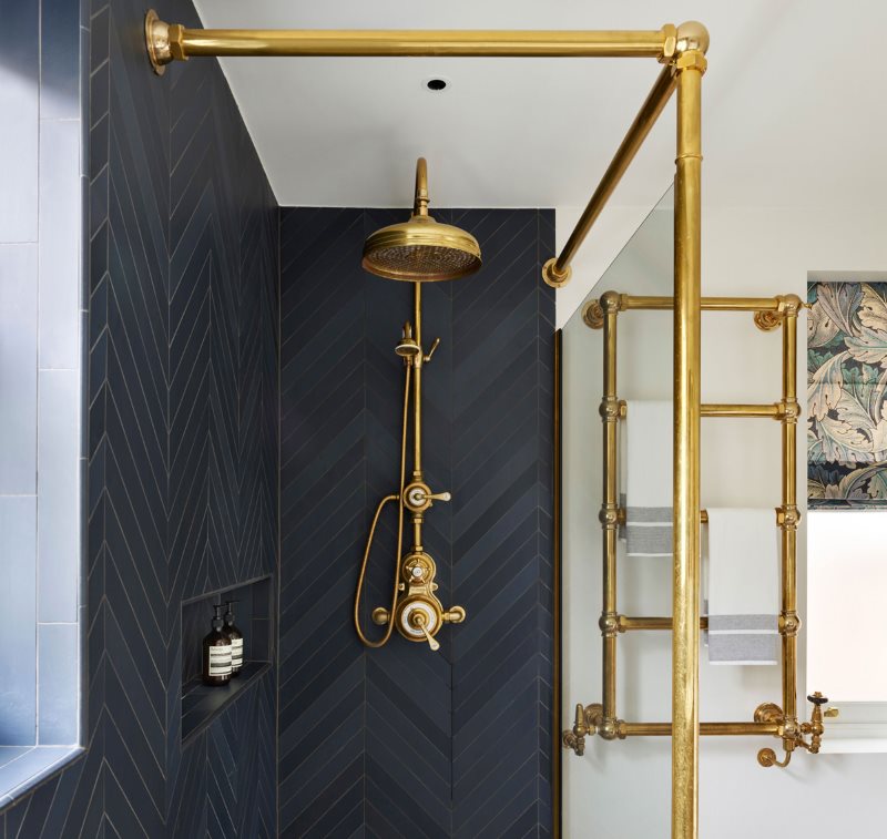 Gold-plated heated towel rail in the bathroom with shower