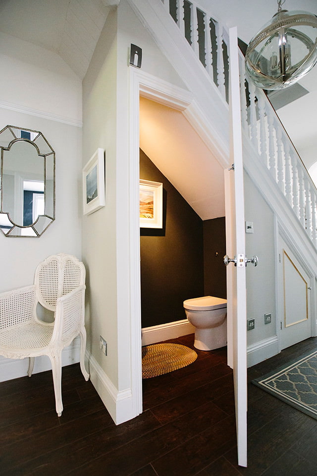 Toilet under the flight of stairs in a wooden house