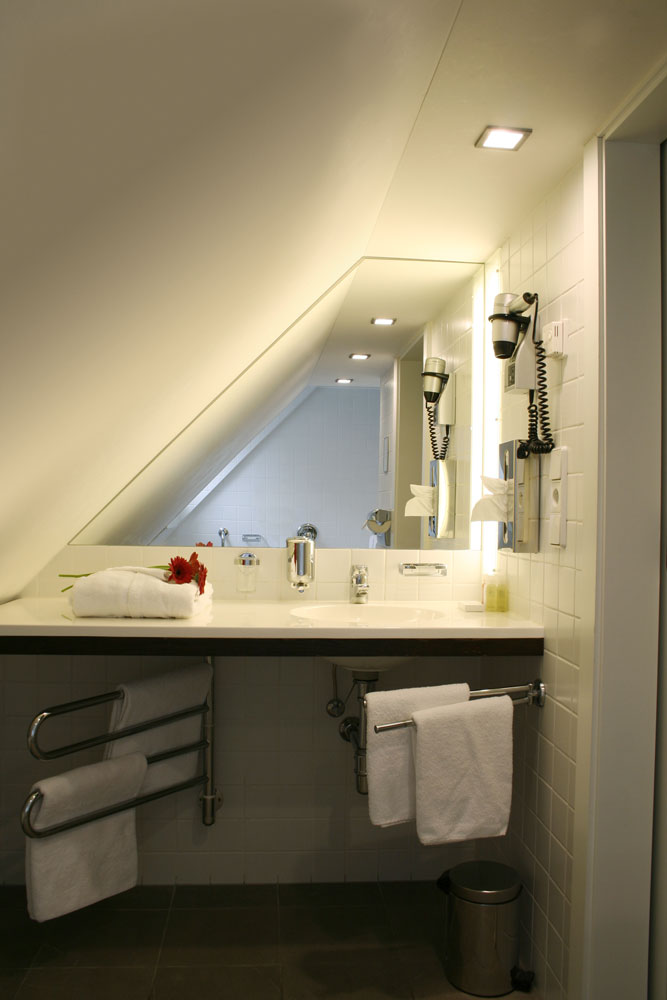 Spotlight on the ceiling of the bathroom under a wooden staircase