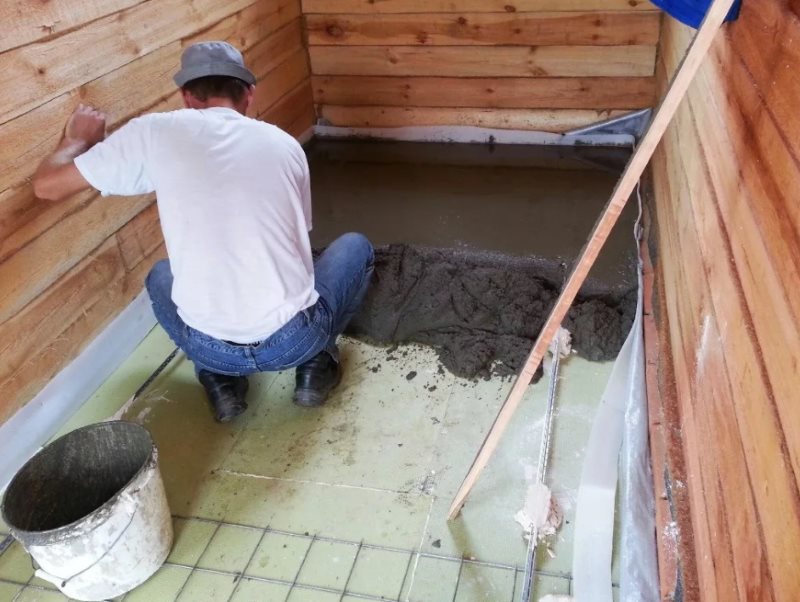 Het apparaat van een betonnen kussen op de badkamervloer in een houten huis