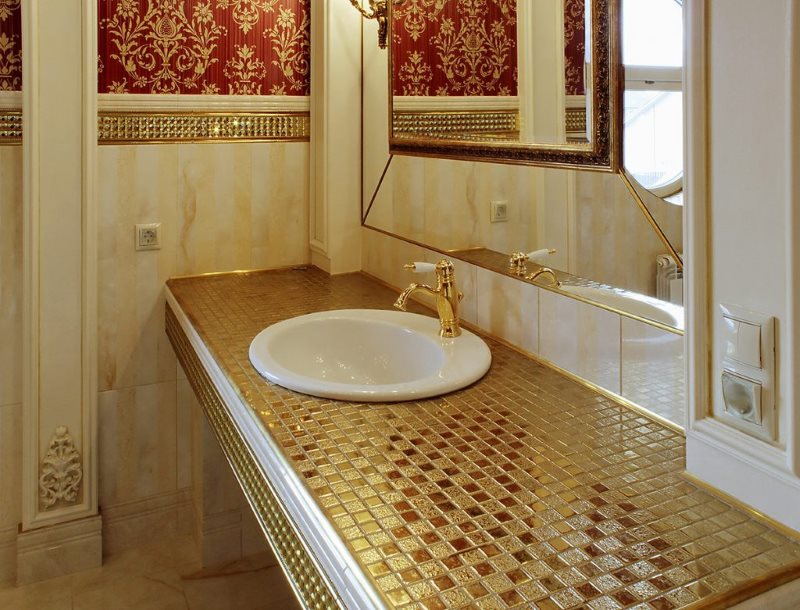 Mosaico con una superficie dorada en la encimera del baño.