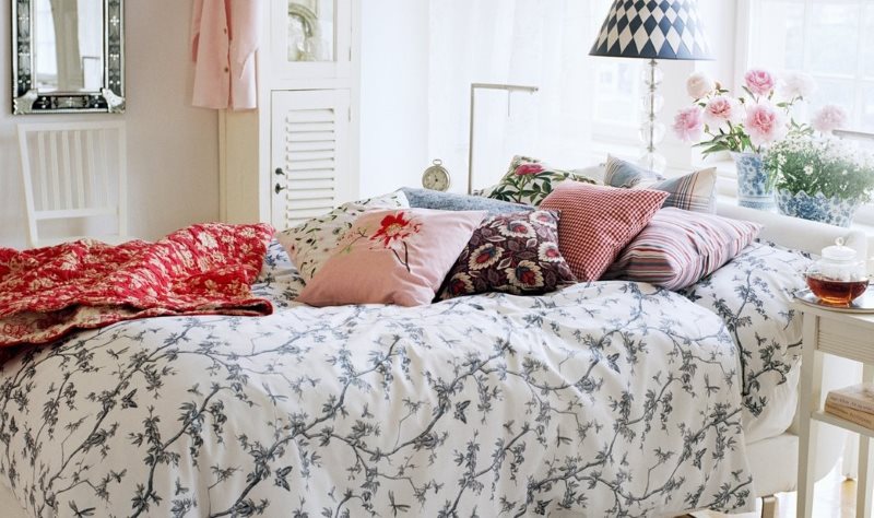 Dekoratív párnák egy ágyon egy rusztikus hálószobában