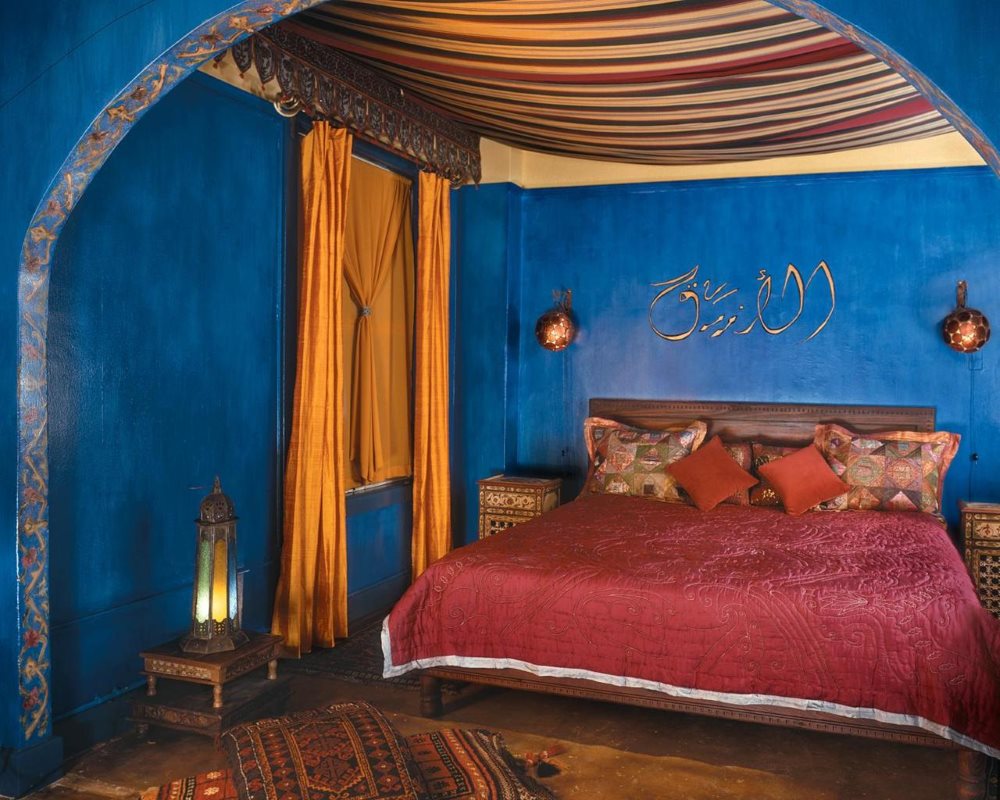 Zilas guļamistabas sienas ar dārgiem tekstilizstrādājumiem