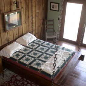 Wide bed on chains in the bedroom of a private house