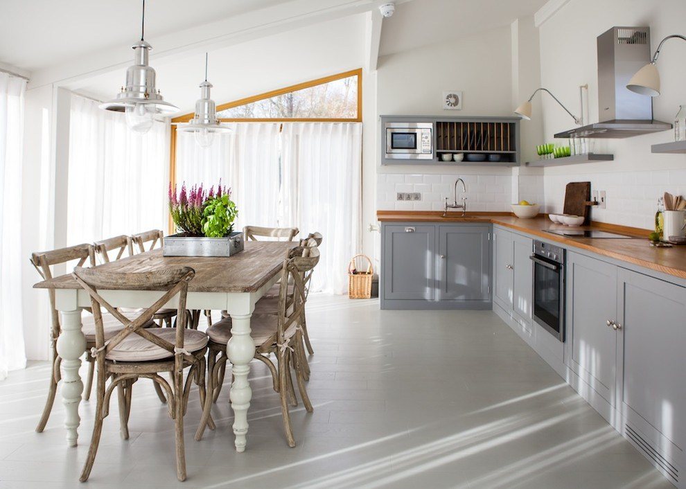 Witte muren in de keuken-woonkamer met een houten tafel